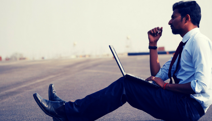 Man sat on a road with a laptop